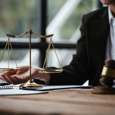 Close up of lawyer's hands and scale of justice on table in the office.