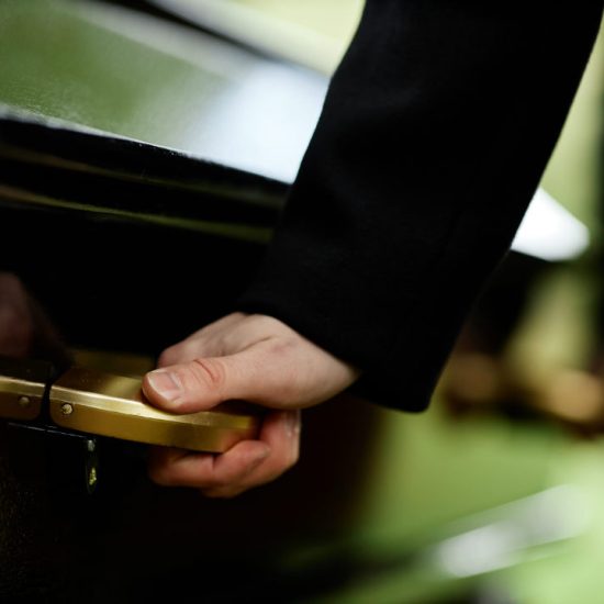 hand-on-coffins-handle-at-outdoor-funeral-2025-03-08-09-08-54-utc-w1080-h1920